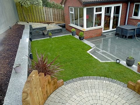 Artificial lawn with a granite sett circle feature and sleeper raised beds