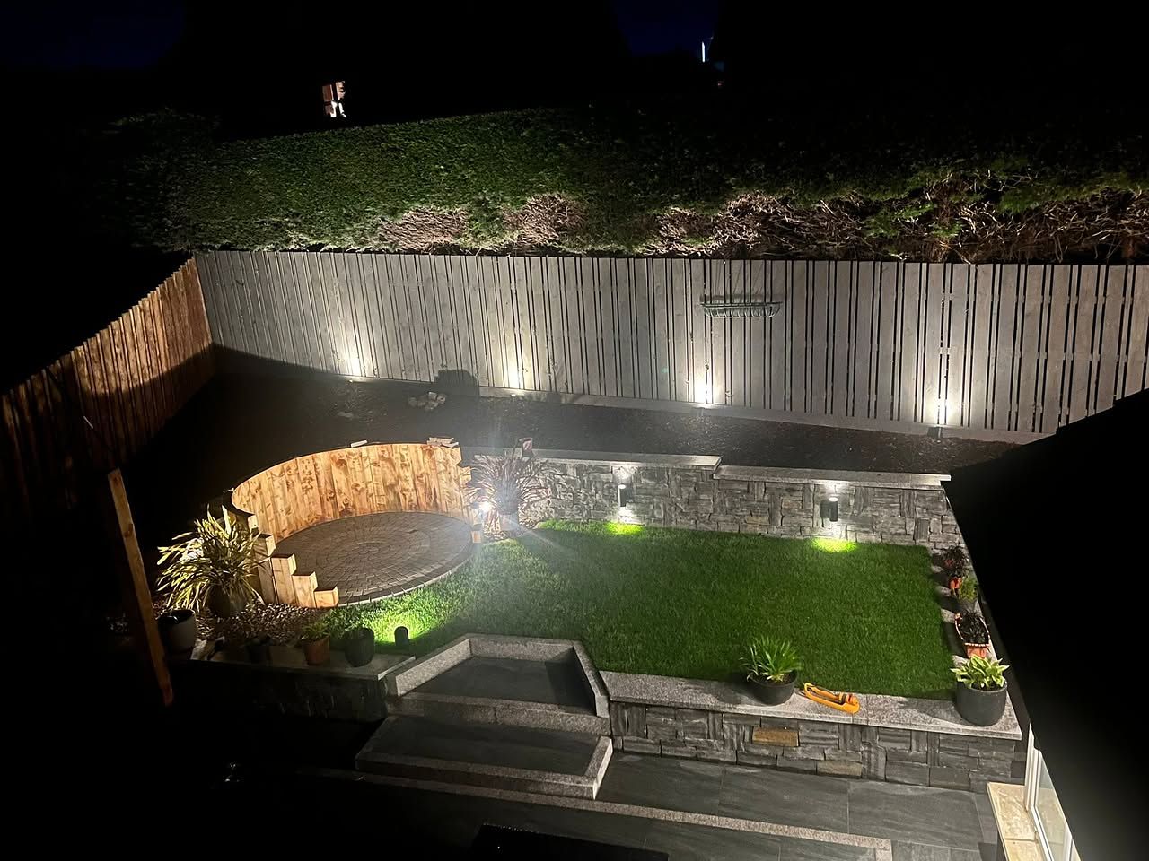 A garden built by S & H Garden Solutions lit at night by its installed lighting scheme
