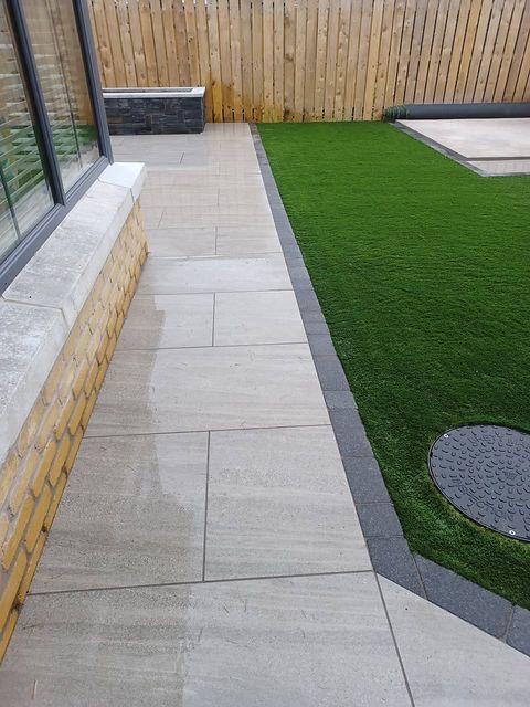 Porcelain paving and artificial lawn with charcoal edging along the side of the house