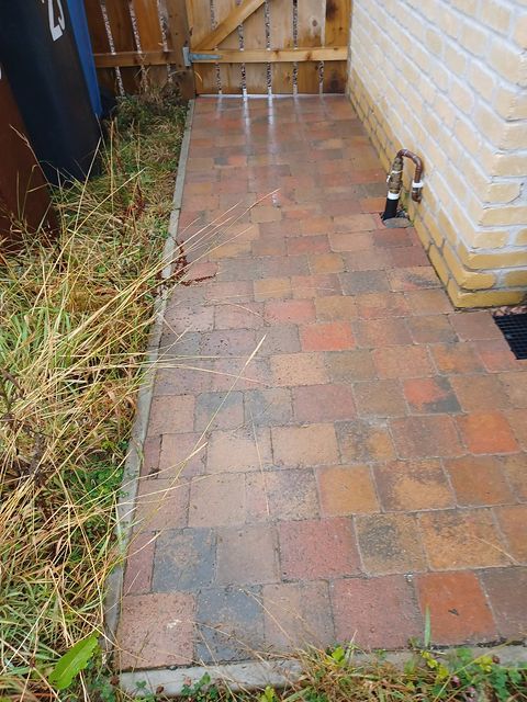 The side return before work, with weed-grown block paving
