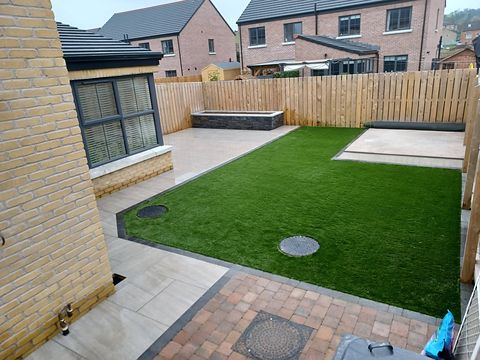 The finished garden: large-format porcelain paving, artificial lawn and a stone-clad raised planter